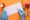 Manos con guantes médicos analizando un trazado de electrocardiograma sobre fondo naranja, junto a estetoscopio y pastillas